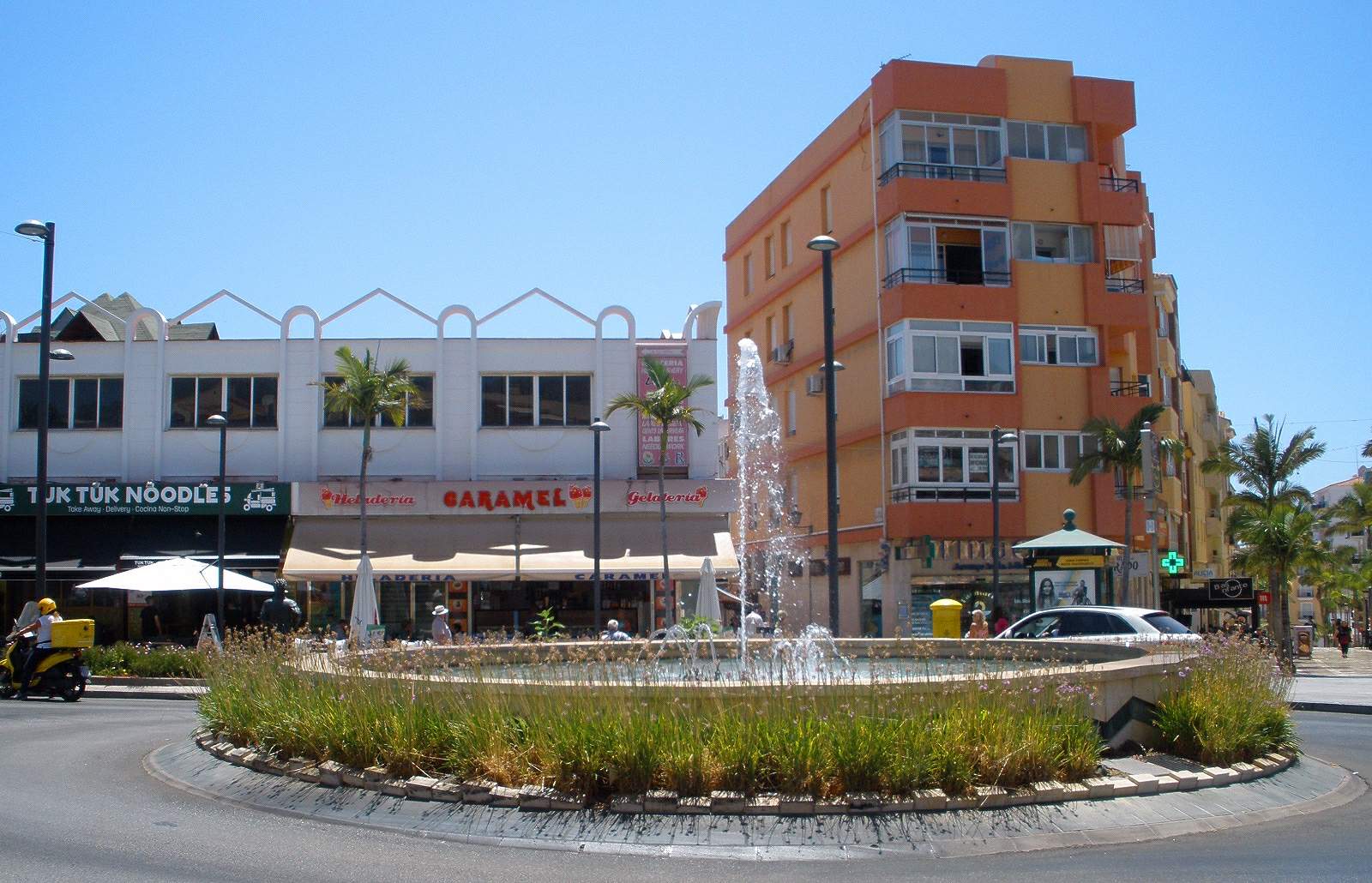 Rotonda con fuente y comercios en el centro de Arroyo de la Miel